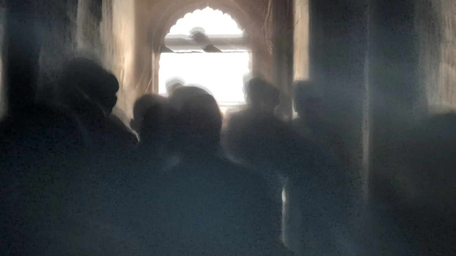 Still from Mid-Breath: figures moving through a dim arched passage.